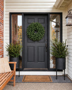Corona de Navidad Alpino verde de 60 cm colgada en una puerta negra de entrada