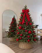 Abeto artificial balsámico de 180 cm Slim decorado con lazo de terciopelo rojo y bolas rojas, con cubrebase de mimbre Ø55 x 26 cm · BOSSVI